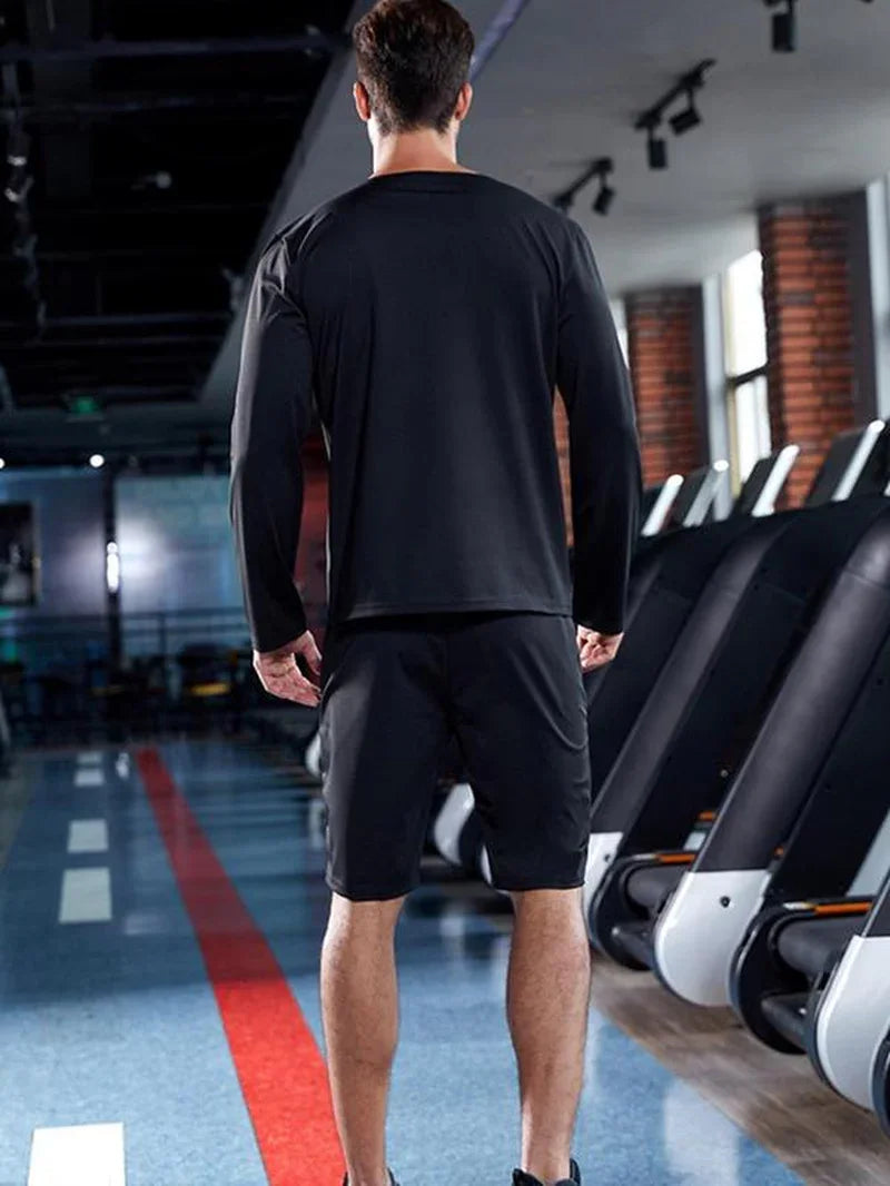Man in black athletic apparel standing in modern gym near treadmills