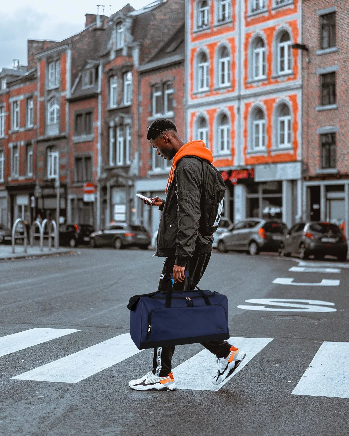 Athletic man with gym duffel bag and sportswear crossing city street